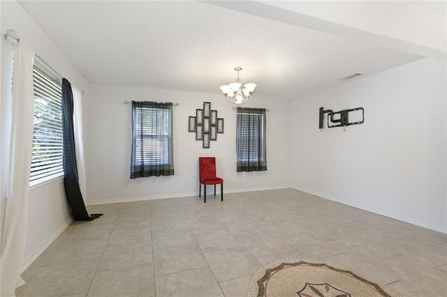 tiled spare room with a chandelier