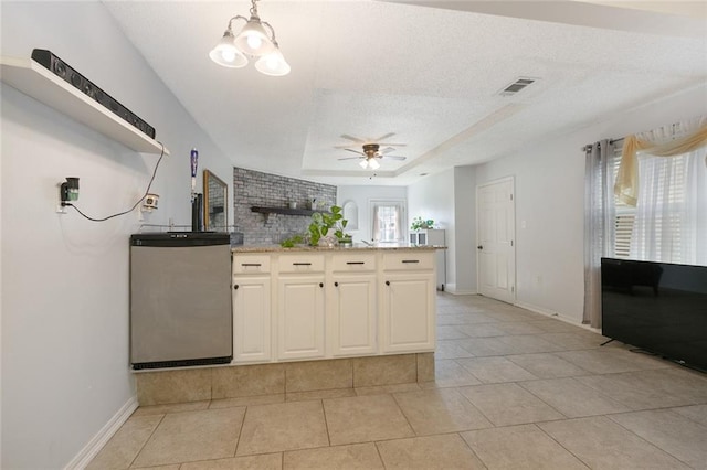 kitchen featuring stainless steel refrigerator, ceiling fan, a textured ceiling, a tray ceiling, and light tile patterned floors