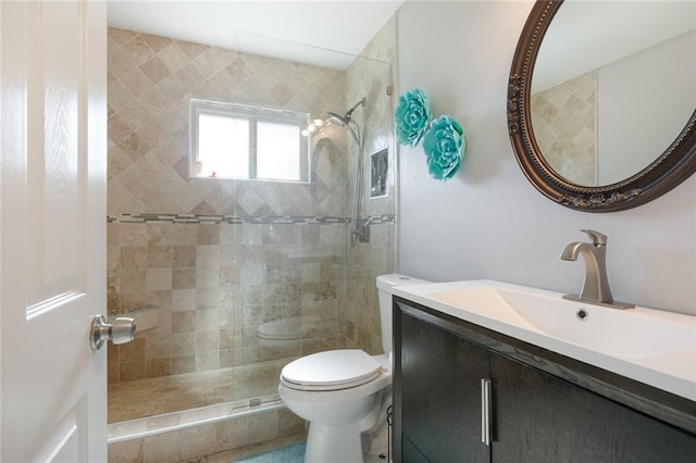 bathroom featuring vanity, toilet, and a tile shower