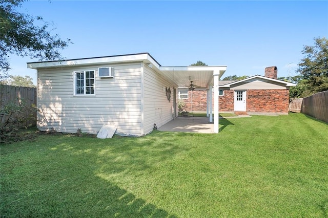 back of house featuring a lawn, ceiling fan, and a patio