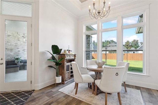 dining room featuring ornamental molding, plenty of natural light, dark wood-type flooring, and a chandelier