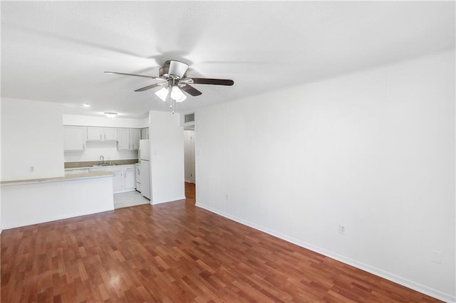 unfurnished living room featuring sink, light wood-type flooring, and ceiling fan