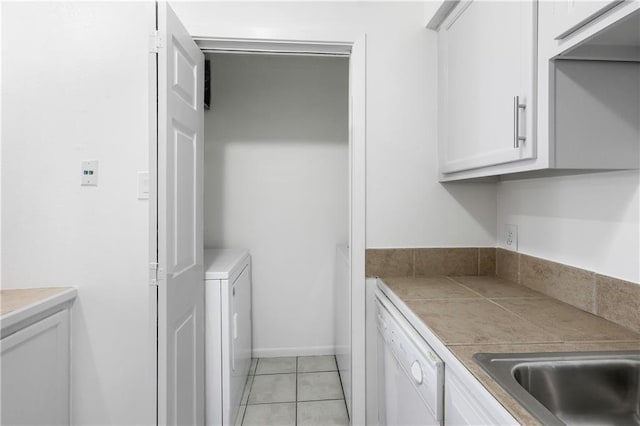 clothes washing area featuring washing machine and dryer, sink, and light tile patterned floors