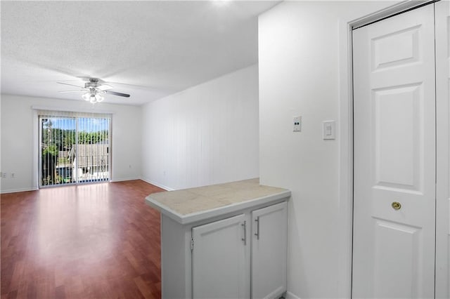 interior space featuring ceiling fan, white cabinets, kitchen peninsula, a textured ceiling, and hardwood / wood-style floors