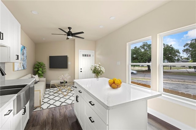 kitchen featuring ceiling fan, dark wood-type flooring, sink, a center island, and white cabinetry