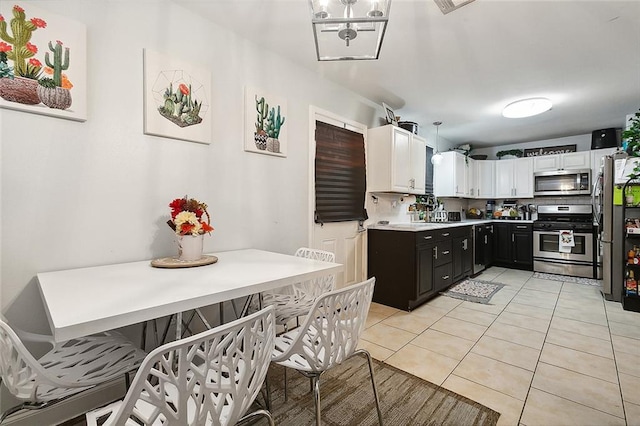 kitchen featuring an inviting chandelier, tasteful backsplash, appliances with stainless steel finishes, light tile patterned floors, and white cabinetry