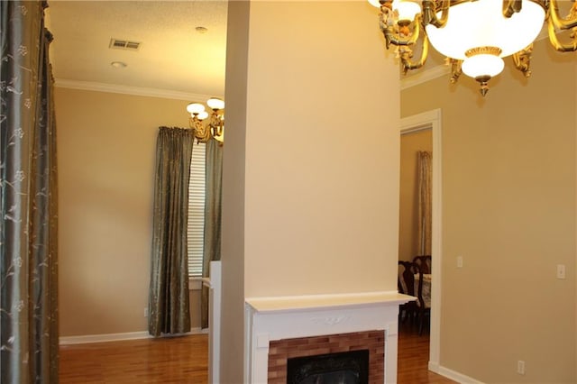 unfurnished living room featuring a notable chandelier, hardwood / wood-style flooring, a fireplace, and ornamental molding