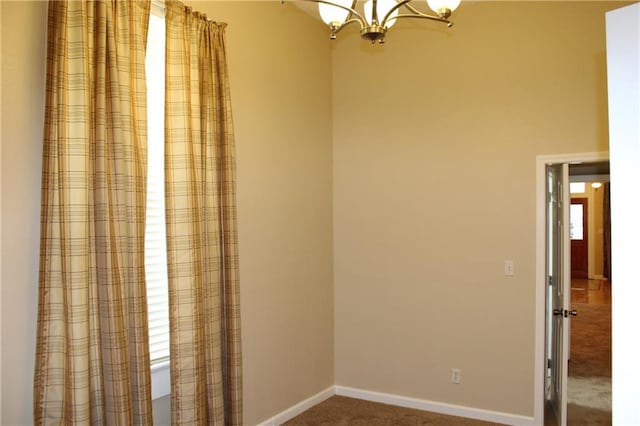 carpeted empty room with a chandelier and a healthy amount of sunlight