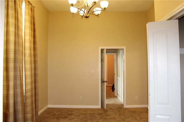 carpeted empty room with a notable chandelier