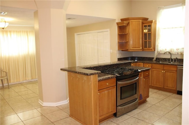 kitchen with plenty of natural light, appliances with stainless steel finishes, sink, and dark stone counters