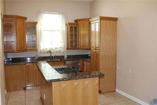 kitchen with sink, light tile patterned floors, stainless steel dishwasher, a center island, and dark stone countertops