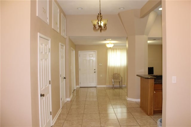 hall with vaulted ceiling, a chandelier, and light tile patterned floors