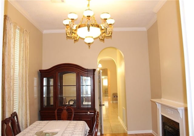 dining area featuring an inviting chandelier, light tile patterned flooring, crown molding, and a high end fireplace