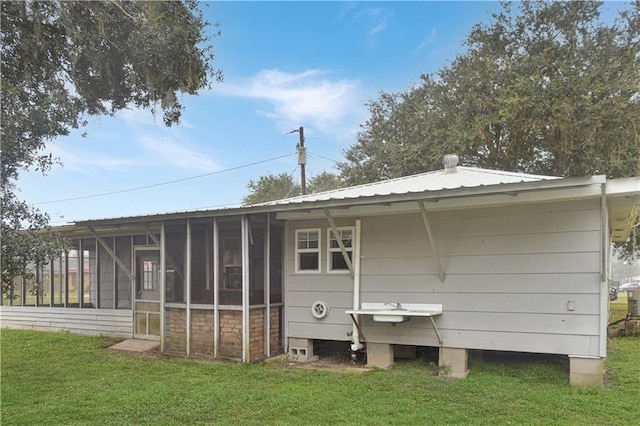 rear view of property featuring a yard and a sunroom