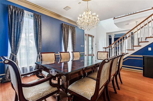 dining space with ornate columns, ornamental molding, a chandelier, and hardwood / wood-style flooring