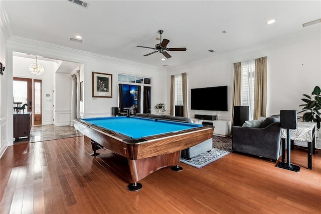 game room featuring hardwood / wood-style flooring, ceiling fan with notable chandelier, ornamental molding, and a healthy amount of sunlight