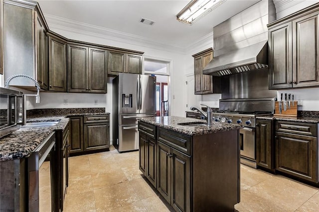 kitchen featuring dark stone counters, a center island with sink, sink, ornamental molding, and appliances with stainless steel finishes