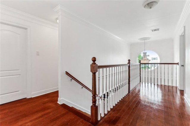 stairway with ornamental molding, hardwood / wood-style floors, and an inviting chandelier