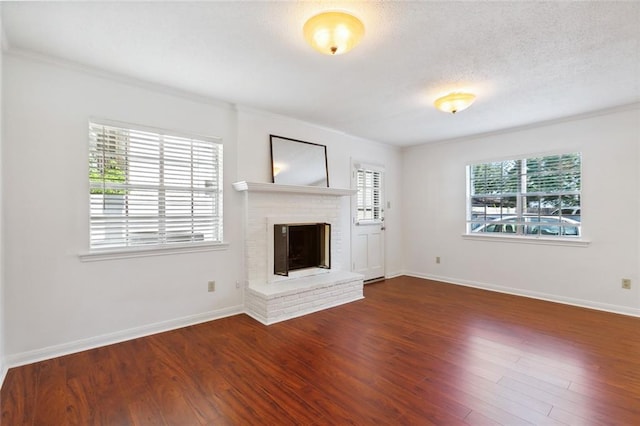 unfurnished living room with ornamental molding, a fireplace, plenty of natural light, and dark wood-type flooring