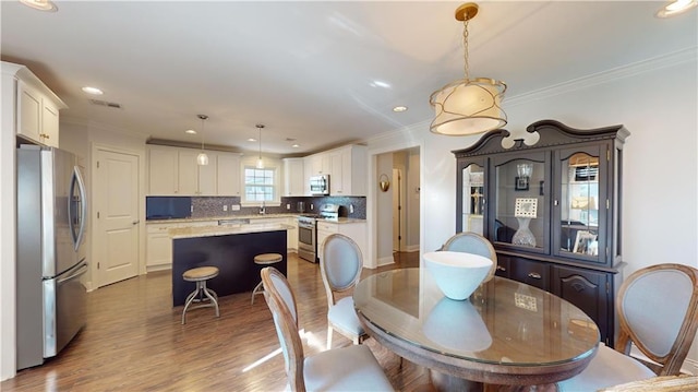 dining space with hardwood / wood-style flooring, crown molding, and sink