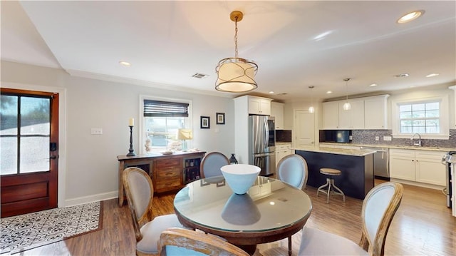 dining room featuring light hardwood / wood-style floors, sink, and ornamental molding