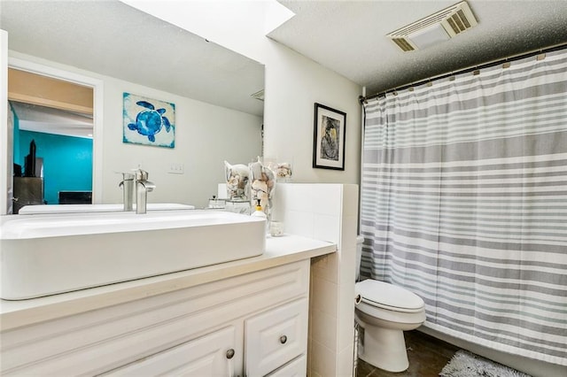 bathroom with vanity, a textured ceiling, curtained shower, and toilet