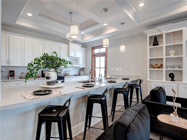 kitchen featuring pendant lighting, ornamental molding, a breakfast bar area, and white cabinetry