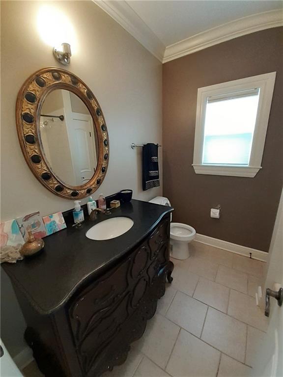 bathroom featuring tile patterned flooring, crown molding, vanity, and toilet