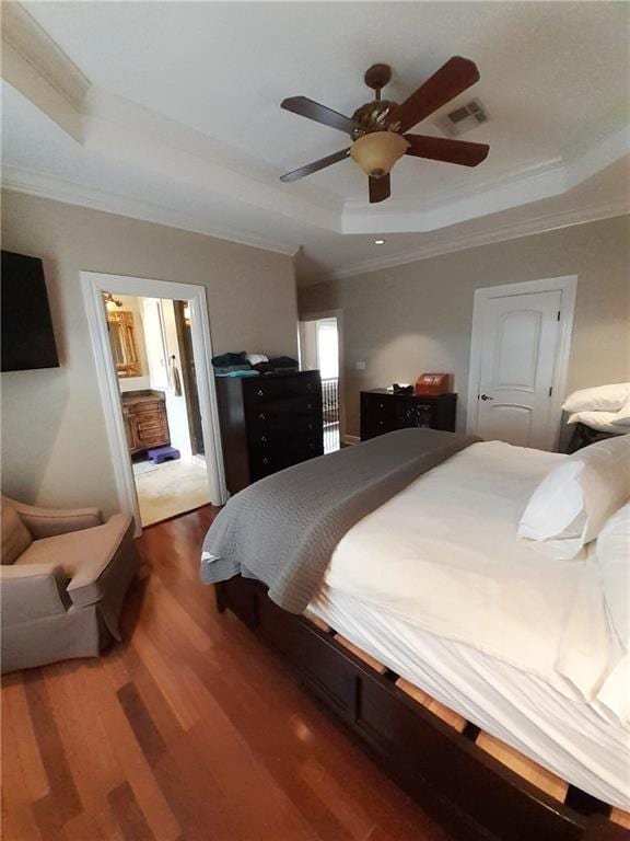 bedroom featuring ornamental molding, a tray ceiling, dark hardwood / wood-style flooring, and ceiling fan