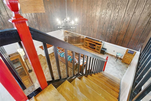 stairway with a chandelier and wooden walls