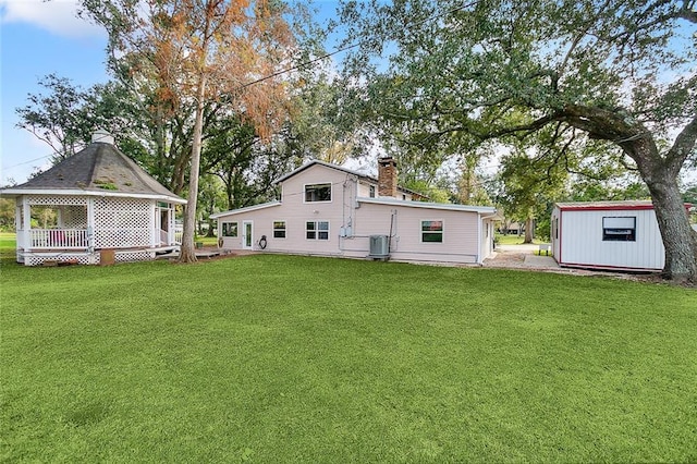 back of property with a shed, cooling unit, and a lawn