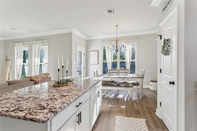 kitchen featuring light stone counters, a kitchen island, white cabinetry, dark hardwood / wood-style floors, and an inviting chandelier