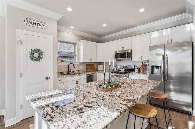 kitchen with dark hardwood / wood-style floors, appliances with stainless steel finishes, a center island, and white cabinetry