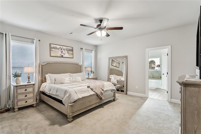 bedroom with ceiling fan, connected bathroom, and light colored carpet