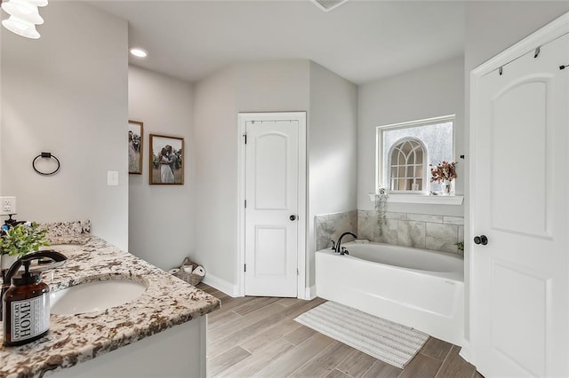 bathroom featuring a tub to relax in, vanity, and wood-type flooring