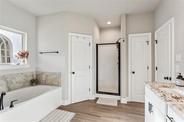 bathroom with vanity, shower with separate bathtub, and hardwood / wood-style floors