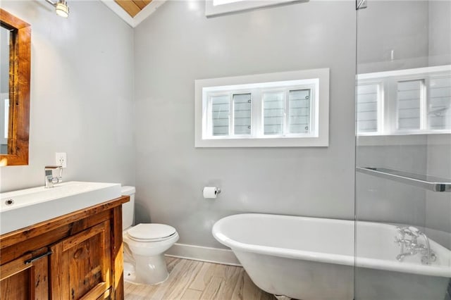 bathroom featuring toilet, hardwood / wood-style floors, vaulted ceiling, a bathing tub, and vanity