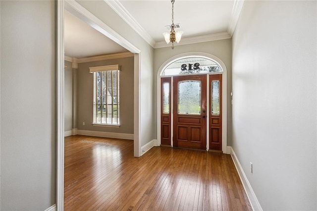 entrance foyer with wood-type flooring, crown molding, and an inviting chandelier