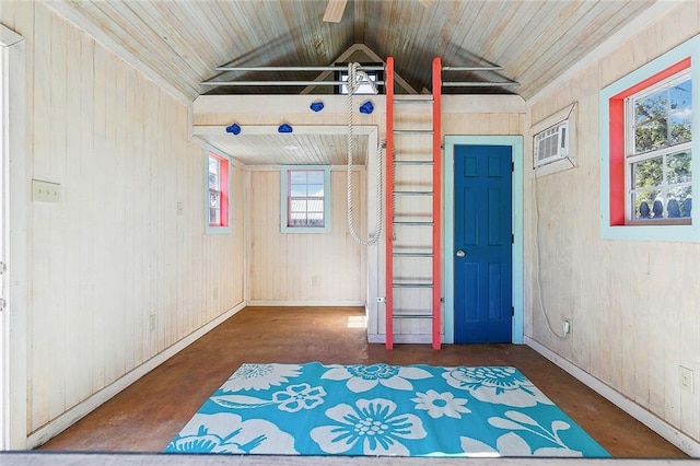 empty room featuring wooden walls, plenty of natural light, and vaulted ceiling