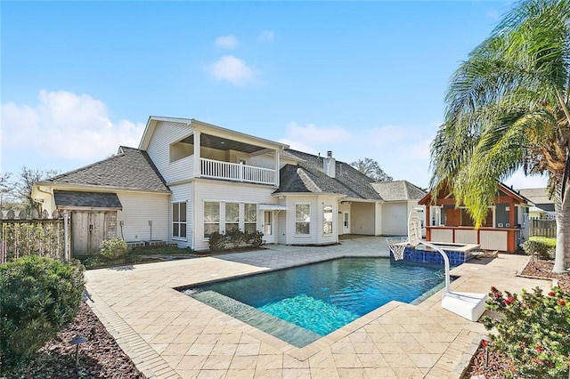 back of house with a fenced in pool, a patio, and a balcony