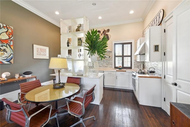 kitchen with decorative backsplash, dark hardwood / wood-style floors, crown molding, wall chimney range hood, and white cabinetry