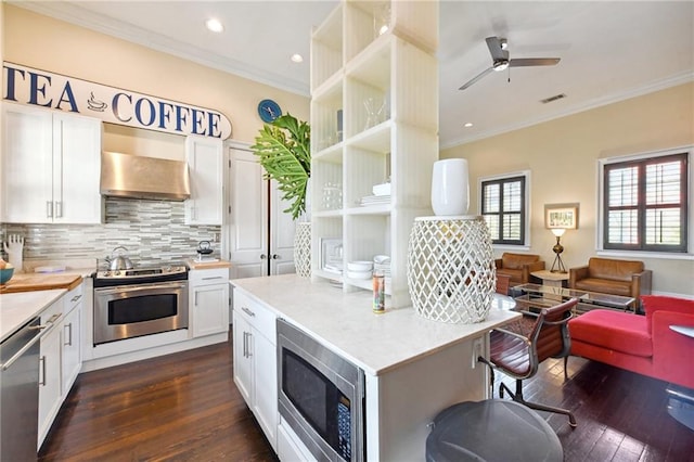 kitchen featuring stainless steel appliances, crown molding, dark wood-type flooring, and white cabinetry