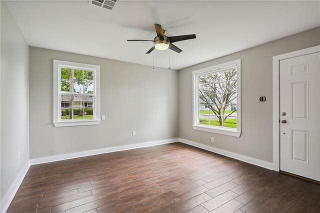 unfurnished room with a wealth of natural light, dark wood-type flooring, and ceiling fan