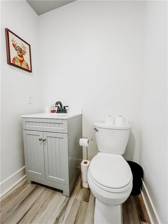 bathroom with hardwood / wood-style floors, toilet, and vanity