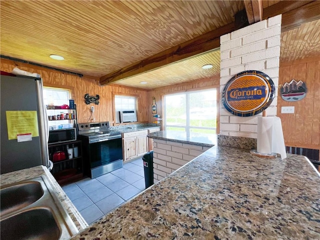 kitchen featuring stainless steel appliances, light tile patterned floors, beamed ceiling, and wooden walls