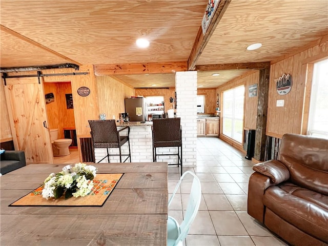 tiled living room featuring a barn door, wood walls, and wooden ceiling