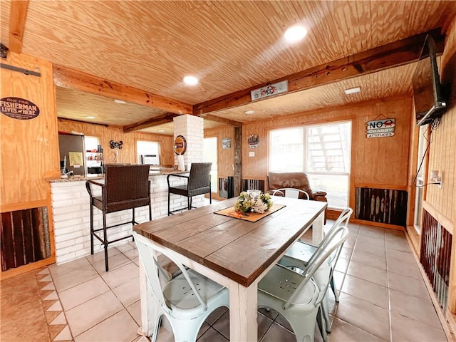 dining space with beam ceiling, wood walls, wood ceiling, and light tile patterned floors