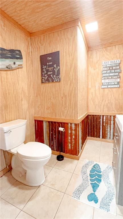 bathroom with tile patterned flooring, toilet, wooden ceiling, wooden walls, and vanity