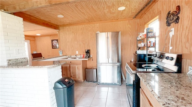 kitchen with beamed ceiling, light stone counters, kitchen peninsula, appliances with stainless steel finishes, and light tile patterned floors