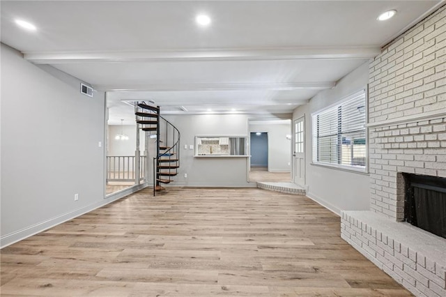 unfurnished living room featuring a fireplace, beamed ceiling, and light hardwood / wood-style flooring